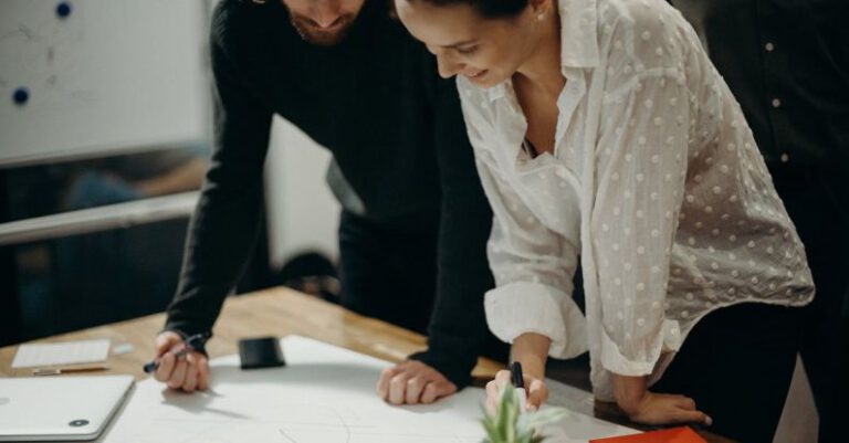 Skill Development - Man and Woman Leaning on Table Staring at White Board on Top of Table Having a Meeting