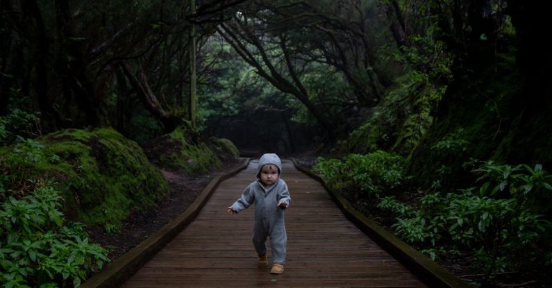 Growth Goals - Concentrated kid trying making steps on planked footpath in dark deep forest in cold day